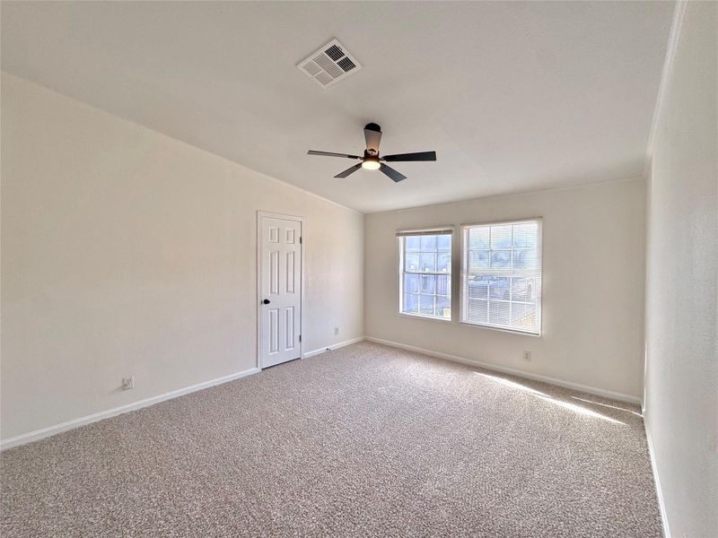 Plentiful natural light streams across the textured carpet through a pair of multi-pane windows.