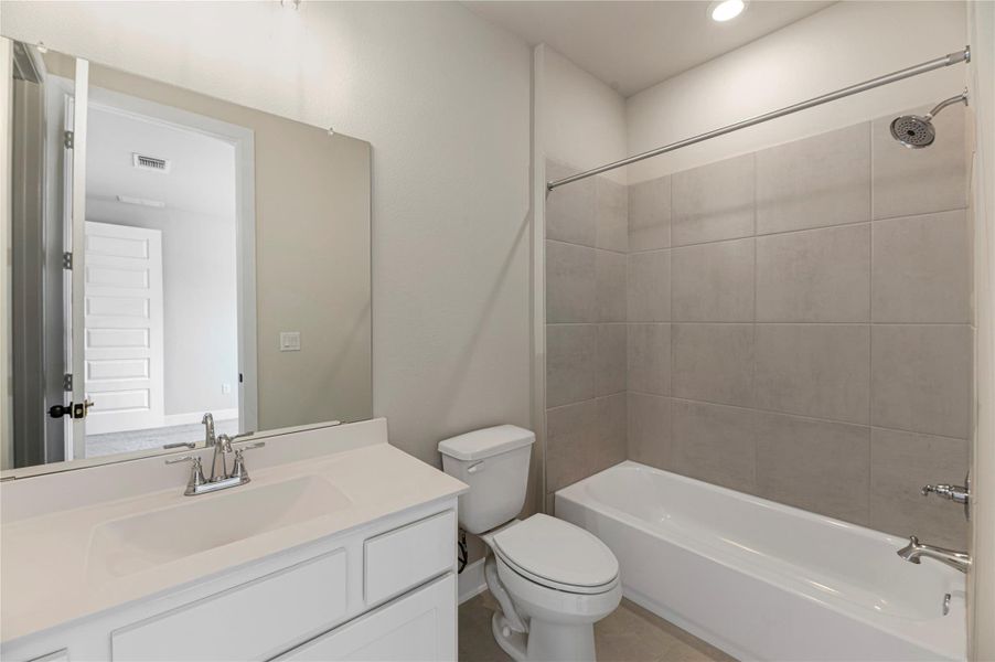 Bathroom with washtub / shower combination, vanity, and light tile patterned floors