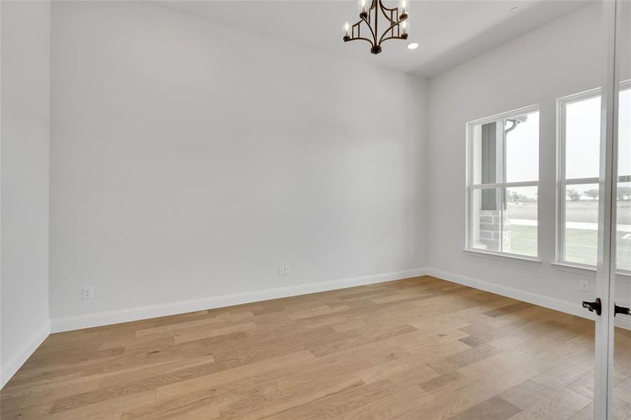 Spare room with a notable chandelier and light wood-type flooring