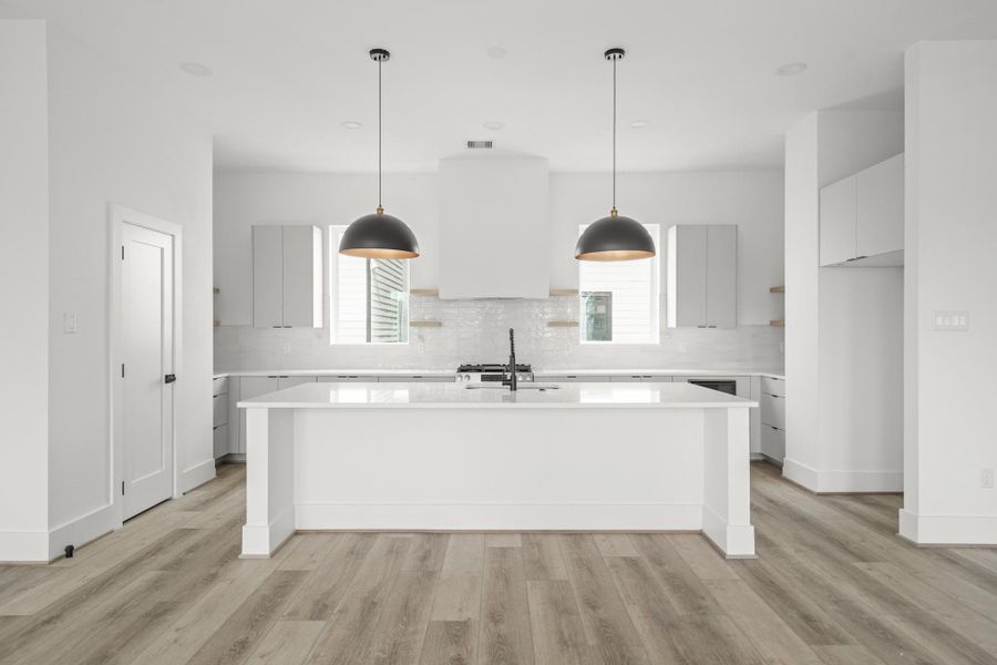 The gourmet kitchen is centered around a large quartz island featuring breakfast bar seating, two oversized pendant lights and a stainless steel undermount sink with a matte black faucet. The gourmet kitchen is centered around a large quartz island featuring breakfast bar seating, two oversized pendant lights and a stainless steel undermount sink with a matte black faucet.