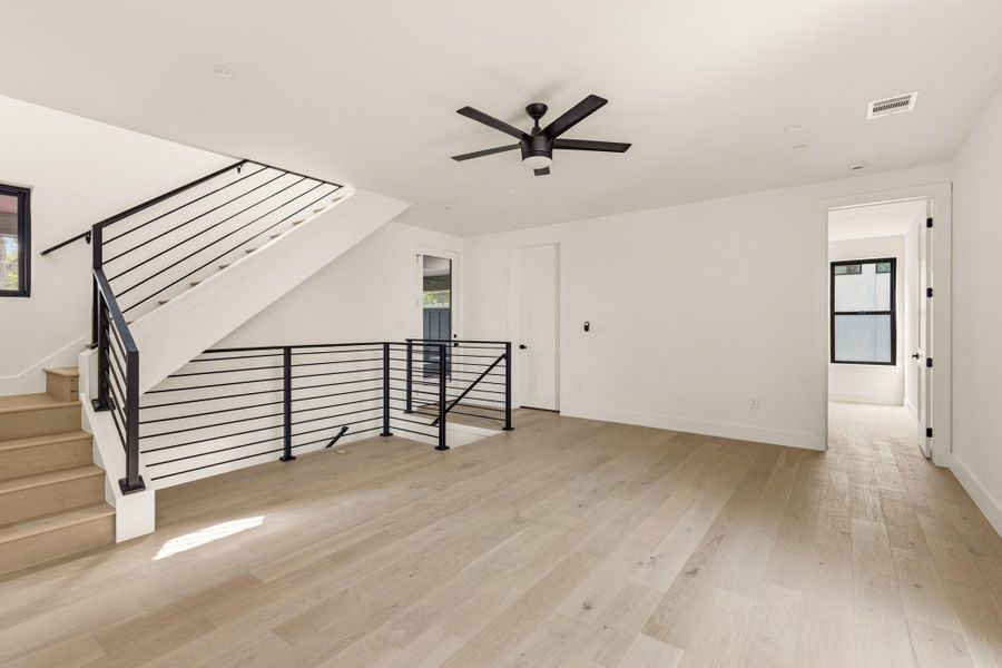 Open-concept room featuring wood-finish flooring and a modern black ceiling fan