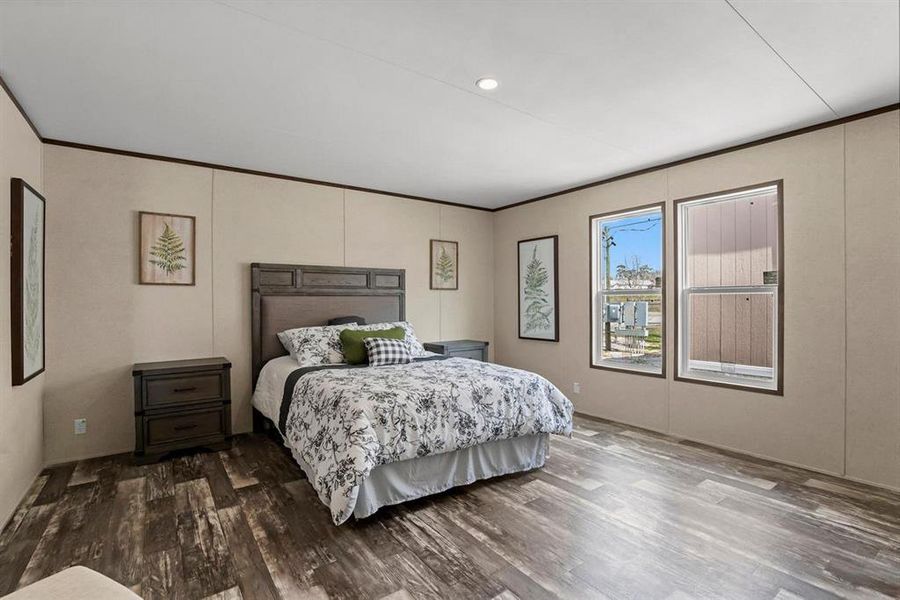 Bedroom with wood finished floors, crown molding, a decorative wall, and recessed lighting