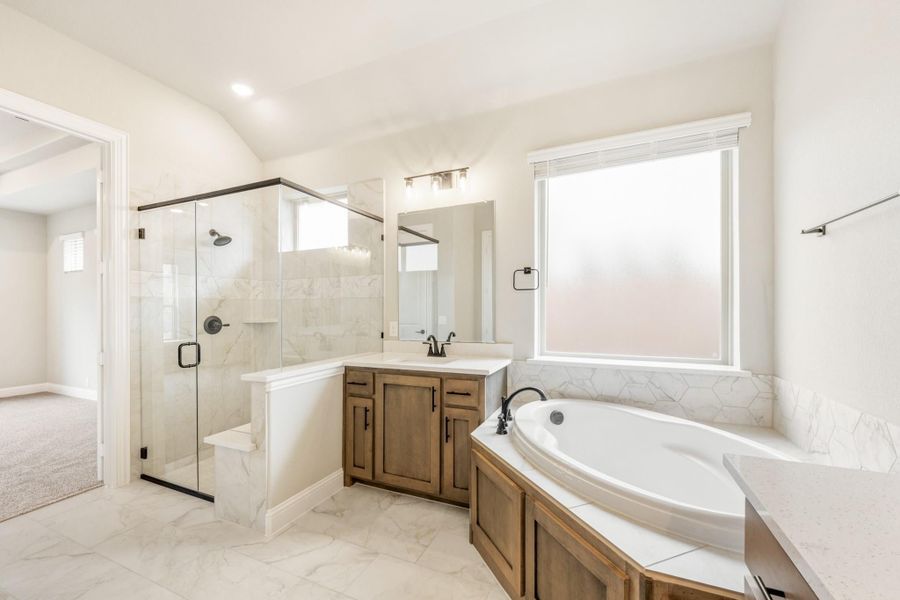 Master bathroom with corner soaking tub, glass walk-in shower, and wood vanity on marble tile floors Master bathroom with corner soaking tub, glass walk-in shower, and wood vanity on marble tile floors