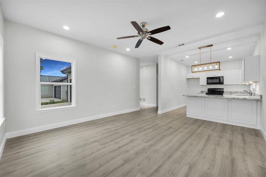 Unfurnished living room featuring recessed lighting, light wood finished floors, visible vents, and baseboards Unfurnished living room featuring recessed lighting, light wood finished floors, visible vents, and baseboards
