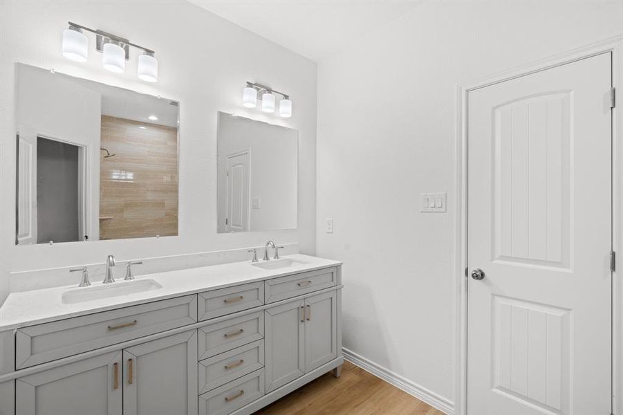 Full bath featuring double vanity, wood finished floors, and a tile shower Full bath featuring double vanity, wood finished floors, and a tile shower