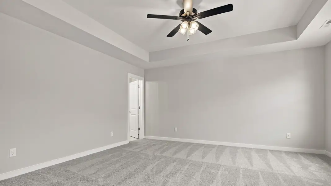 Spacious primary bedroom with elevated tray ceiling feature