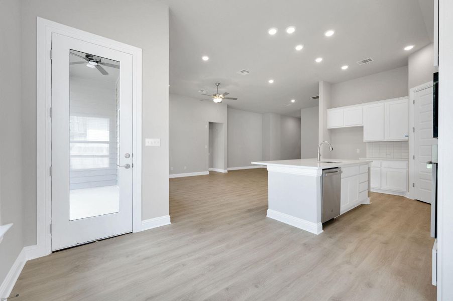 Kitchen featuring ceiling fan, white cabinetry, light wood-style flooring, recessed lighting, and an island with sink