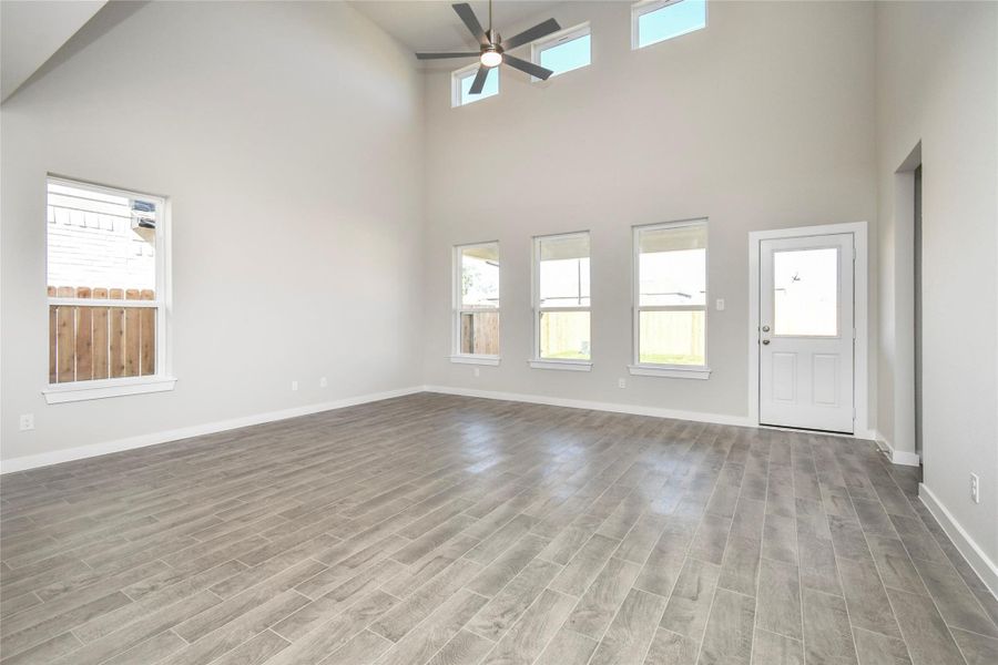 Gather the family and guests together in your lovely living room! Featuring soaring highceilings, recessed lighting, ceiling fan, custom paint, gorgeous floors, and large windows thatprovide plenty of natural lighting throughout the day. Sample photo of completed home with similar floor plan. Actual colors and selections may vary.