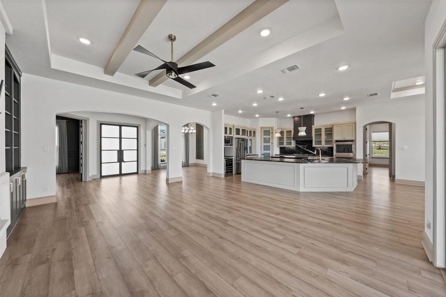 Unfurnished living room with arched walkways, visible vents, light wood-style floors, and a ceiling fan
