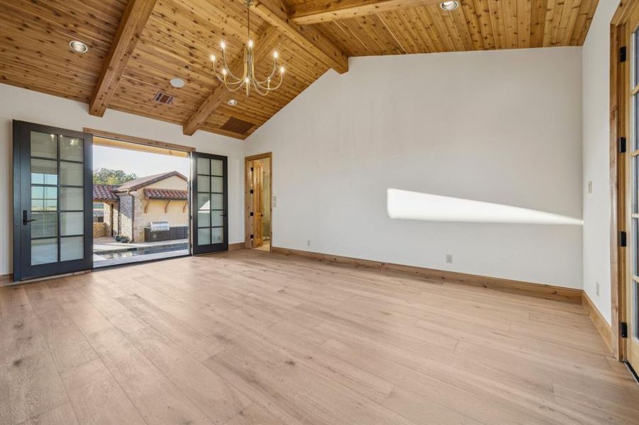 Spare room featuring light wood-style floors, a chandelier, high vaulted ceiling, a wood ceiling with exposed beams, and french doors