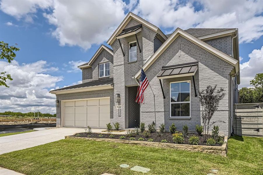 View of front of home with a standing seam roof, concrete driveway, and brick siding View of front of home with a standing seam roof, concrete driveway, and brick siding