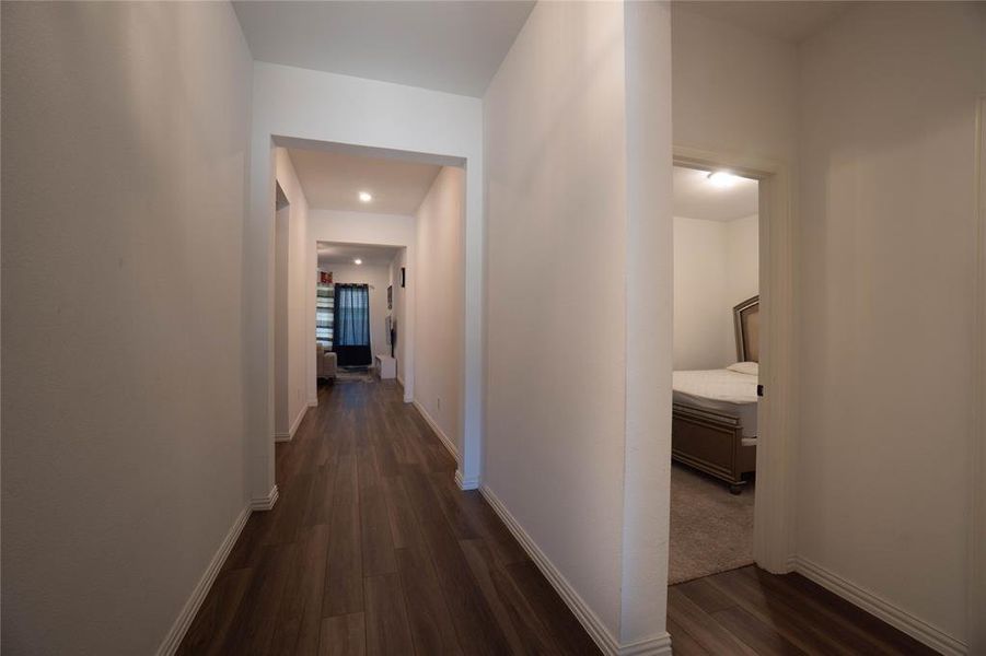 Hallway featuring wood-finish flooring, white baseboards, recessed lighting, and a neutral color palette