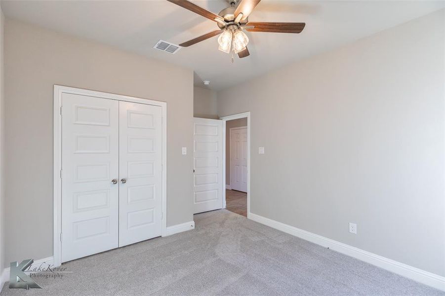 Unfurnished bedroom featuring carpet floors, ceiling fan, and a closet