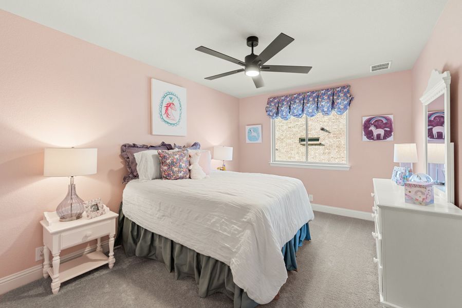 Children's bedroom with pink walls, ceiling fan, carpet, and white dresser with mirror