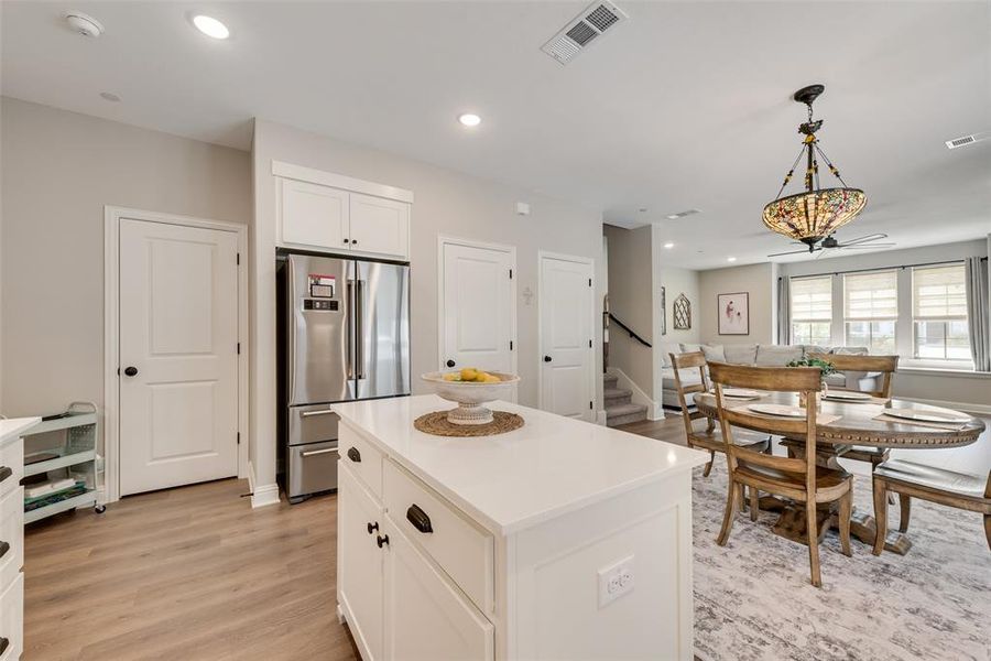 Kitchen featuring hanging light fixtures, high end refrigerator, white cabinets, and light wood-type flooring