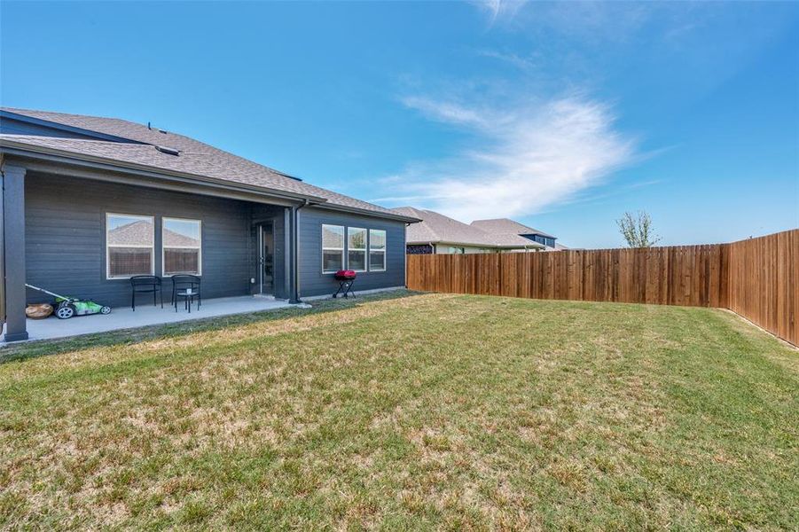 Spacious backyard featuring a full-height wood fence, a large concrete patio, and dark siding on the home's exterior Spacious backyard featuring a full-height wood fence, a large concrete patio, and dark siding on the home's exterior