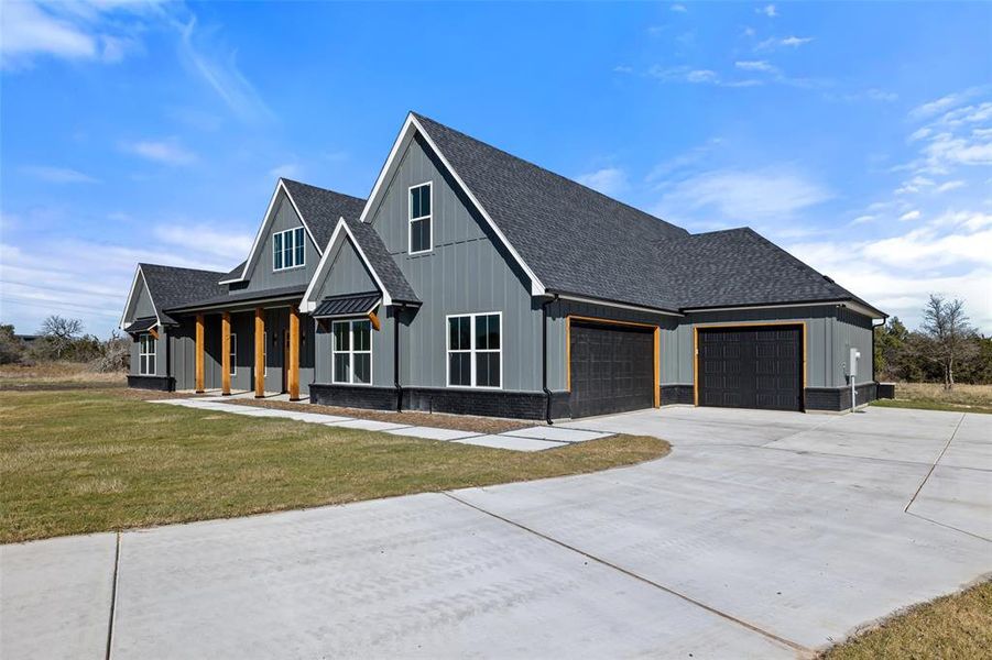 Modern inspired farmhouse featuring a porch, a garage, and a front yard