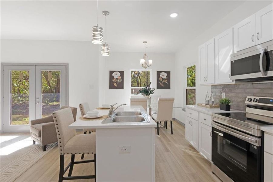 Kitchen featuring a kitchen breakfast bar, sink, white cabinets, and appliances with stainless steel finishes