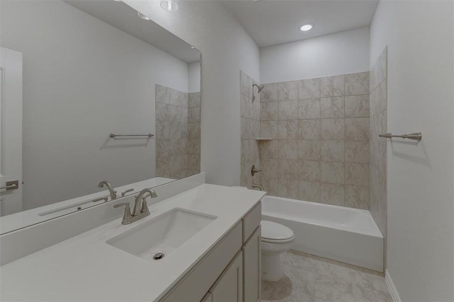 Bathroom featuring a single vanity with an integrated sink and brushed nickel faucet, a large wall-mounted mirror, and a shower-over-tub combination with light-toned wall tile