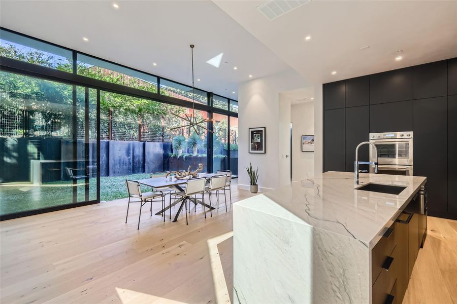 Floor-to-ceiling glass invites garden views into this modern kitchen and dining area with lustrous hardwood floors. Floor-to-ceiling glass invites garden views into this modern kitchen and dining area with lustrous hardwood floors.