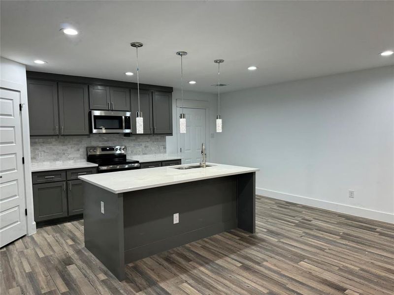 Kitchen with hanging light fixtures, sink, appliances with stainless steel finishes, and dark hardwood / wood-style flooring