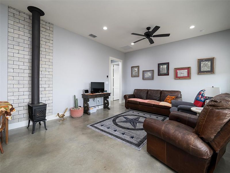 Living area with a wood stove, finished concrete floors, recessed lighting, and a ceiling fan Living area with a wood stove, finished concrete floors, recessed lighting, and a ceiling fan