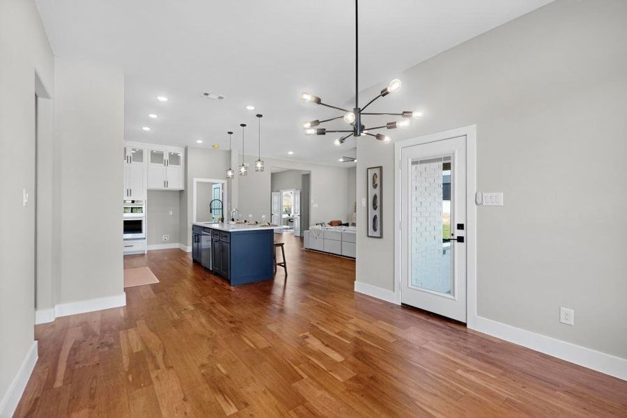 Kitchen with open floor plan, white cabinetry, a chandelier, wood finished floors, and recessed lighting