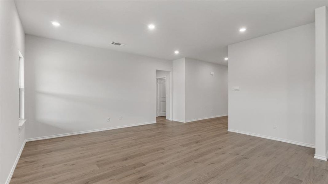 Spacious room featuring wood-finish flooring, recessed lighting, and white baseboards