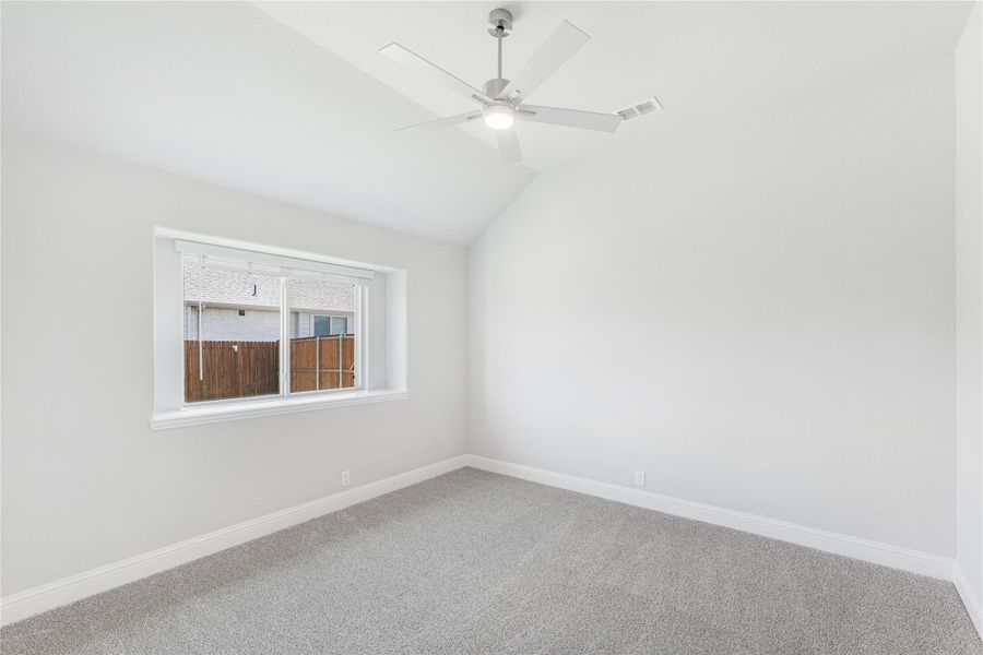 Empty bedroom with vaulted ceiling, ceiling fan, gray carpet, and single window
