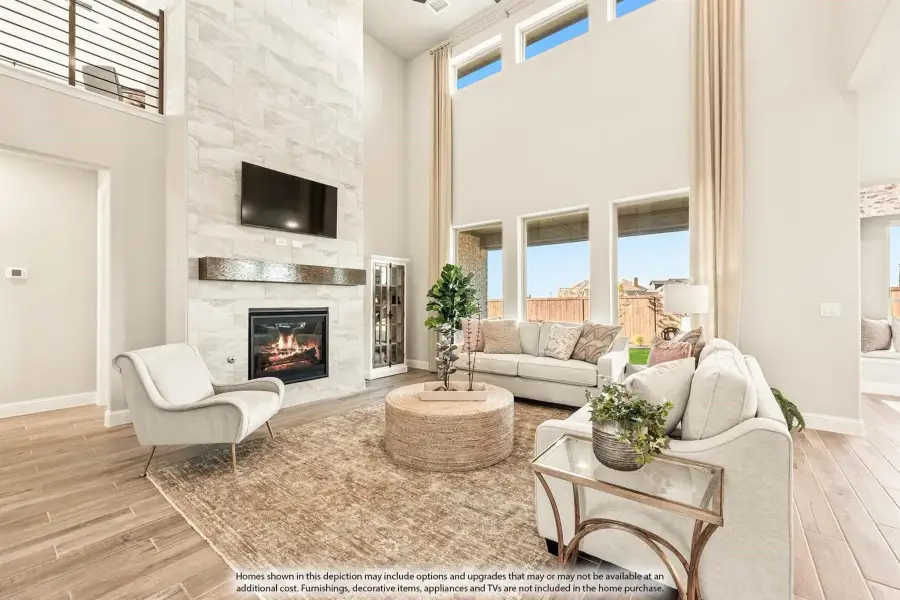 Living room with two-story ceiling, tile fireplace wall, and large windows with hardwood floors