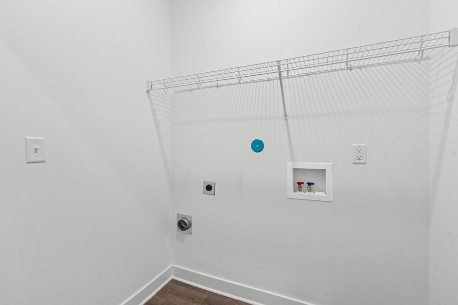 Dedicated laundry area featuring a wire storage shelf, utility hookups, and wood-finish flooring