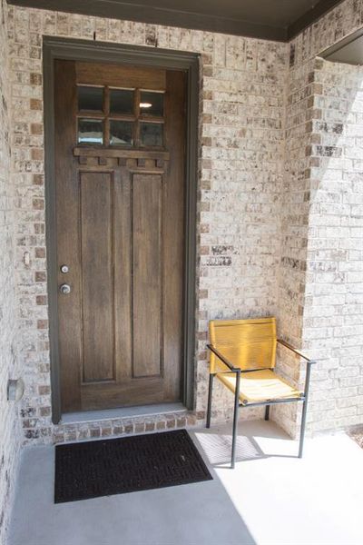 Entrance to property featuring brick siding and a patio area