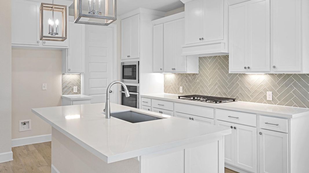 Kitchen with hanging light fixtures, a kitchen island with sink, tasteful backsplash, white cabinetry, and stainless steel appliances