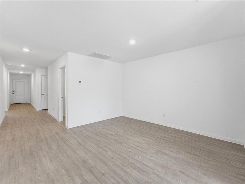 Spacious room featuring light wood-finish flooring, white walls, and recessed lighting