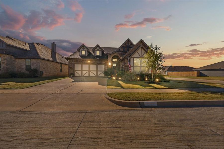 English style home featuring concrete driveway, a front yard, and brick siding