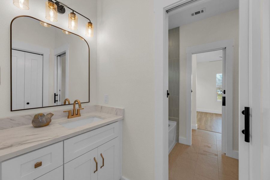 Bathroom featuring vanity, light tile patterned flooring, and a bathtub