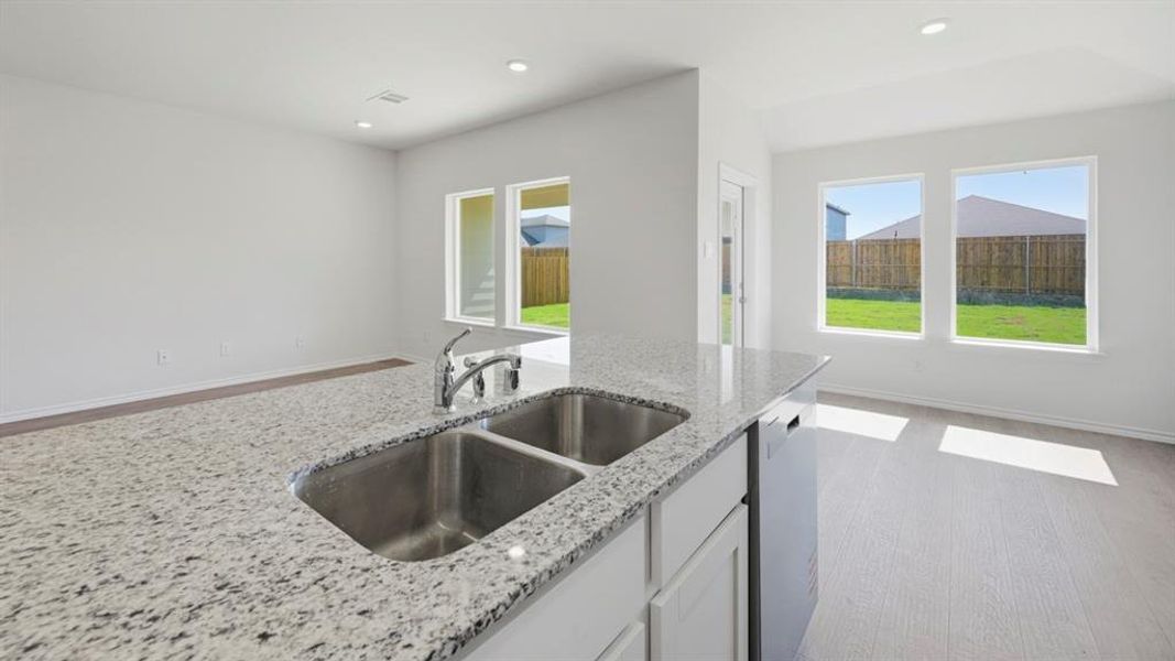 Kitchen with white cabinetry, light wood-style floors, healthy amount of natural light, light stone countertops, and recessed lighting