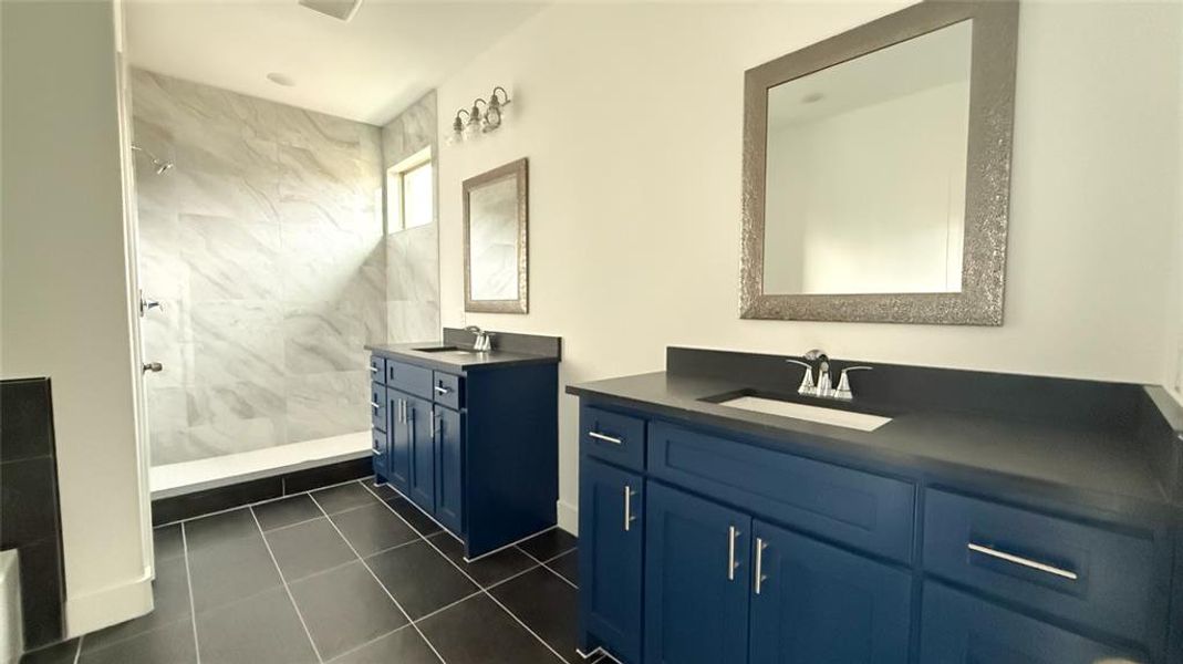 Bathroom with a tile shower, two vanities, and a sink