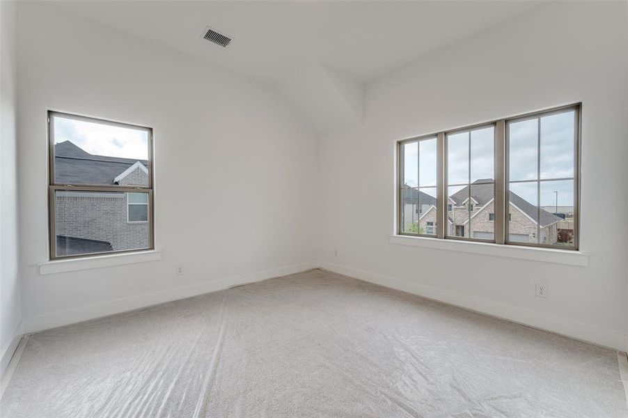 Carpeted empty room featuring lofted ceiling