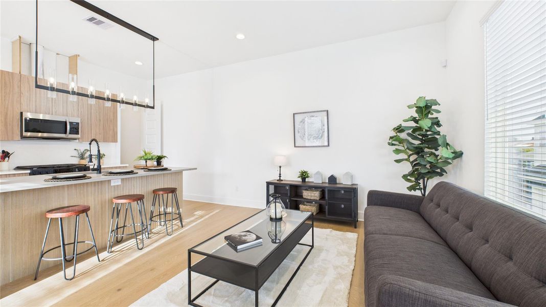 The welcoming second-floor open-concept living area seamlessly combines the living room, dining room, and kitchen, filled with natural light and enhanced by modern finishes and engineered hardwood flooring throughout, creating a bright and inviting space ideal for everyday living and entertaining.