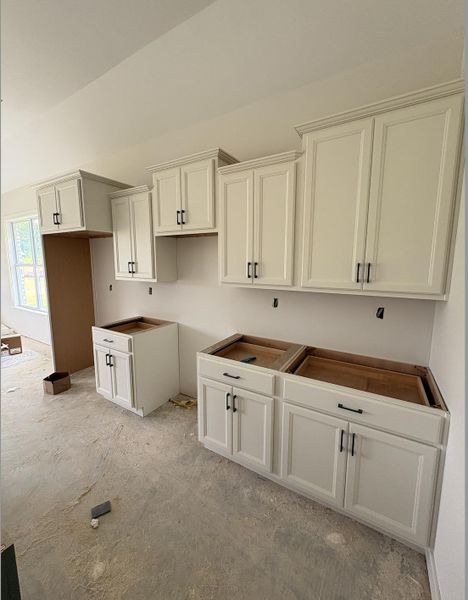 Kitchen featuring white shaker-style cabinetry with crown molding and matte black hardware Kitchen featuring white shaker-style cabinetry with crown molding and matte black hardware