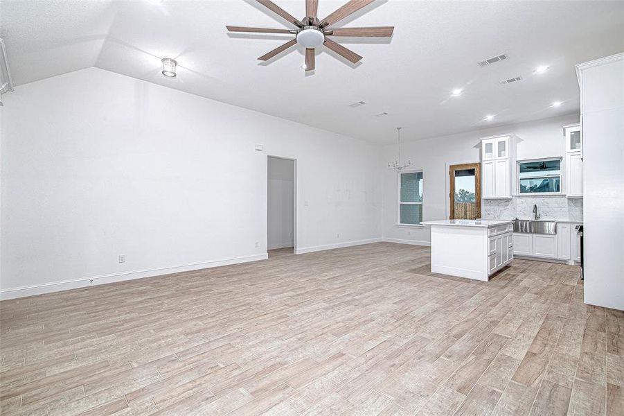 Kitchen with open floor plan, light countertops, a chandelier, a sink, and light wood finished floors Kitchen with open floor plan, light countertops, a chandelier, a sink, and light wood finished floors