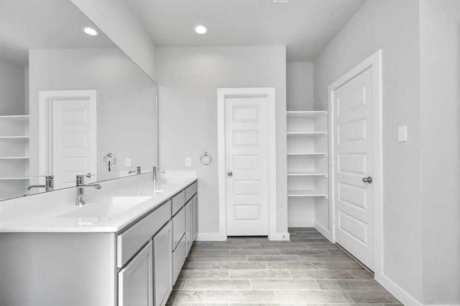 Elevate your daily routine at the elegant vanity, now equipped with double sinks, light countertops, modern hardware, and beautiful vanity lights. Sample photo of completed home with similar floor plan. As-built interior colors and selections may vary.