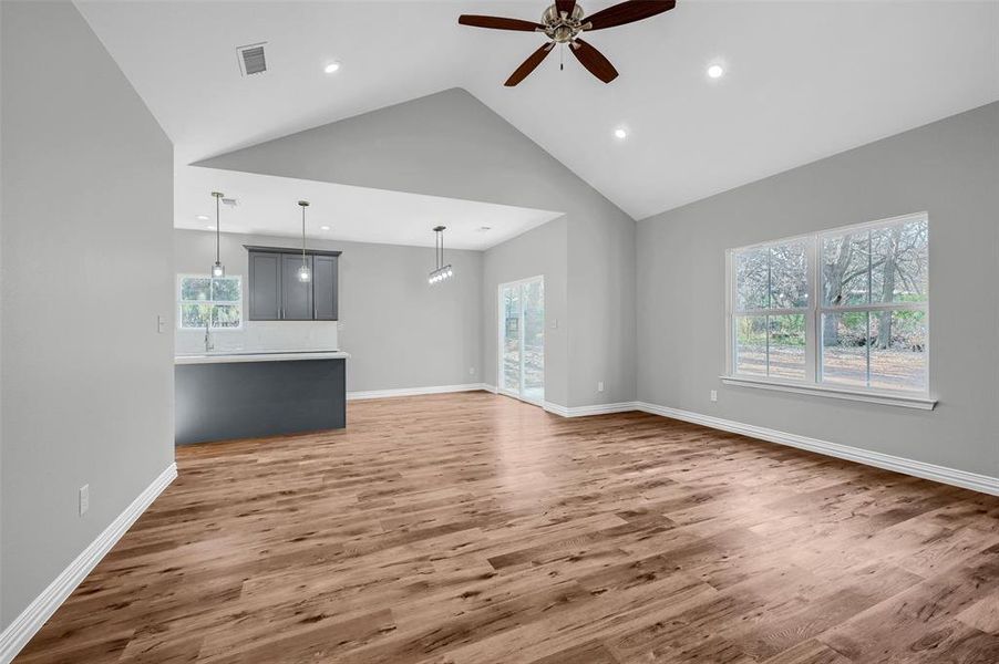 Unfurnished living room with ceiling fan, dark hardwood / wood-style flooring, and high vaulted ceiling