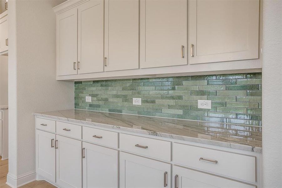 Kitchen featuring white cabinetry, decorative backsplash, and light stone countertops