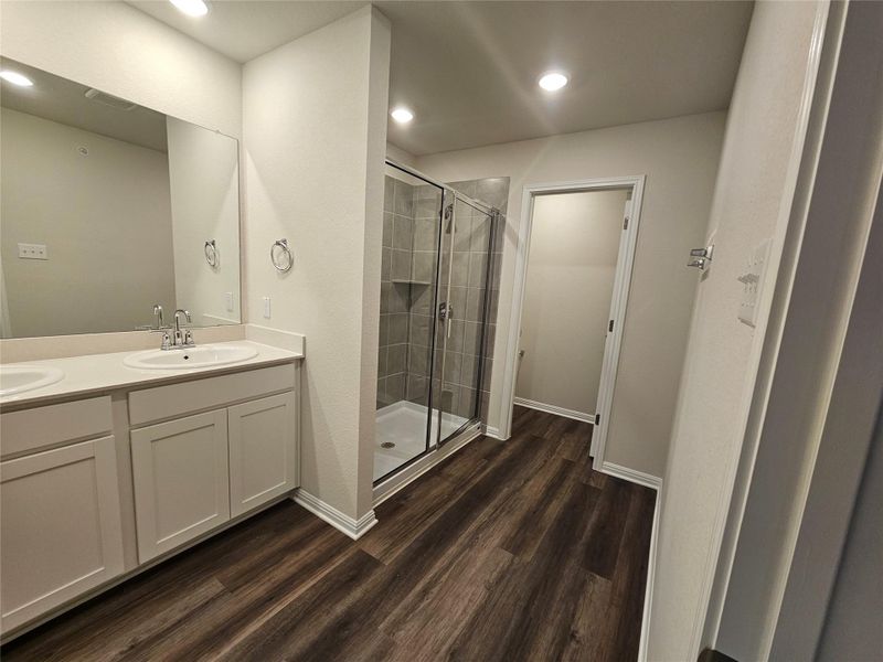 Bathroom featuring double vanity, a shower stall, dark wood finished floors, and recessed lighting Bathroom featuring double vanity, a shower stall, dark wood finished floors, and recessed lighting