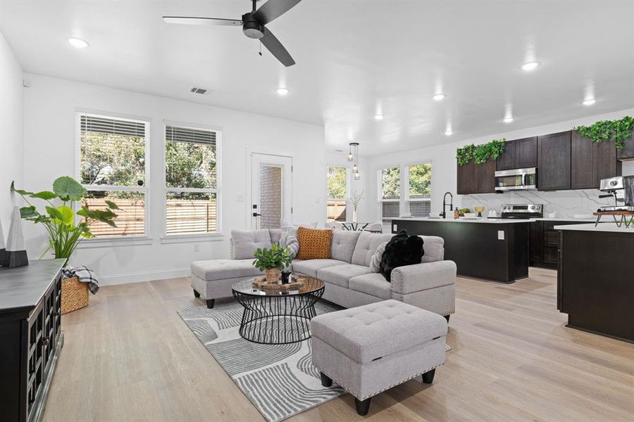 Living room with a wealth of natural light, sink, light hardwood / wood-style flooring, and ceiling fan