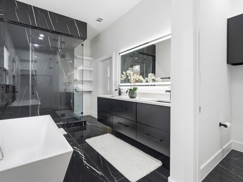 Contemporary bathroom featuring black marble-style flooring and shower surround, a frameless glass shower enclosure, a dual vanity with undermount sinks, and an illuminated mirror