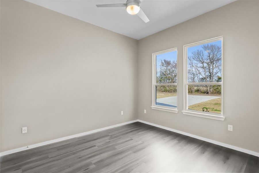 Empty room featuring dark wood-type flooring and ceiling fan