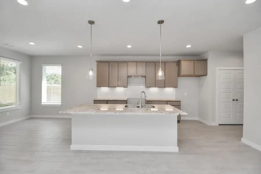 The kitchen is a culinary haven, featuring granite countertops, a tile backsplash, stainless steel appliances, 42” upper cabinets, and undercabinet lighting. Sample photo of completed home with similar floor plan. Actual colors and selections may vary. The kitchen is a culinary haven, featuring granite countertops, a tile backsplash, stainless steel appliances, 42” upper cabinets, and undercabinet lighting. Sample photo of completed home with similar floor plan. Actual colors and selections may vary.